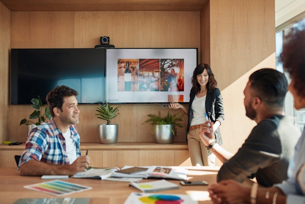  Group of colleagues in a conference room with one giving a presentation.