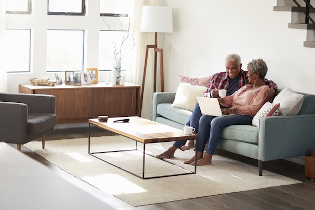 elderly couple sitting on couch with laptop