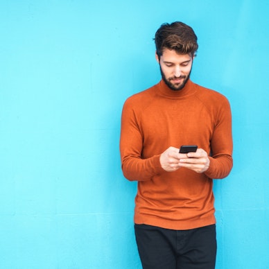man standing looking down at phone
