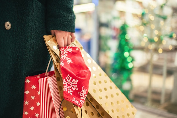 Person holding gift bags while holiday shopping.