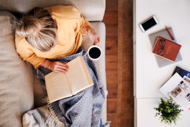 woman reading and holding coffee
