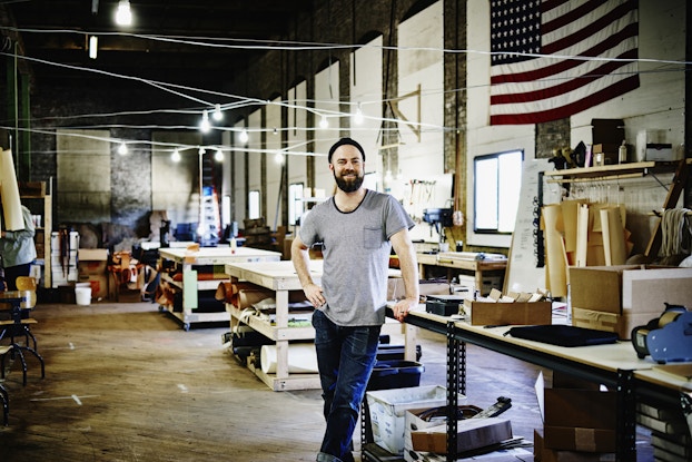  Smiling man inside his leatherworking shop.