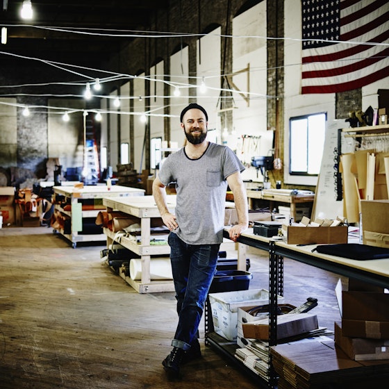 Smiling man inside his leatherworking shop.