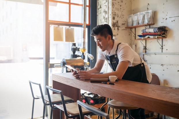 Business owner working inside his cafe on a tablet.