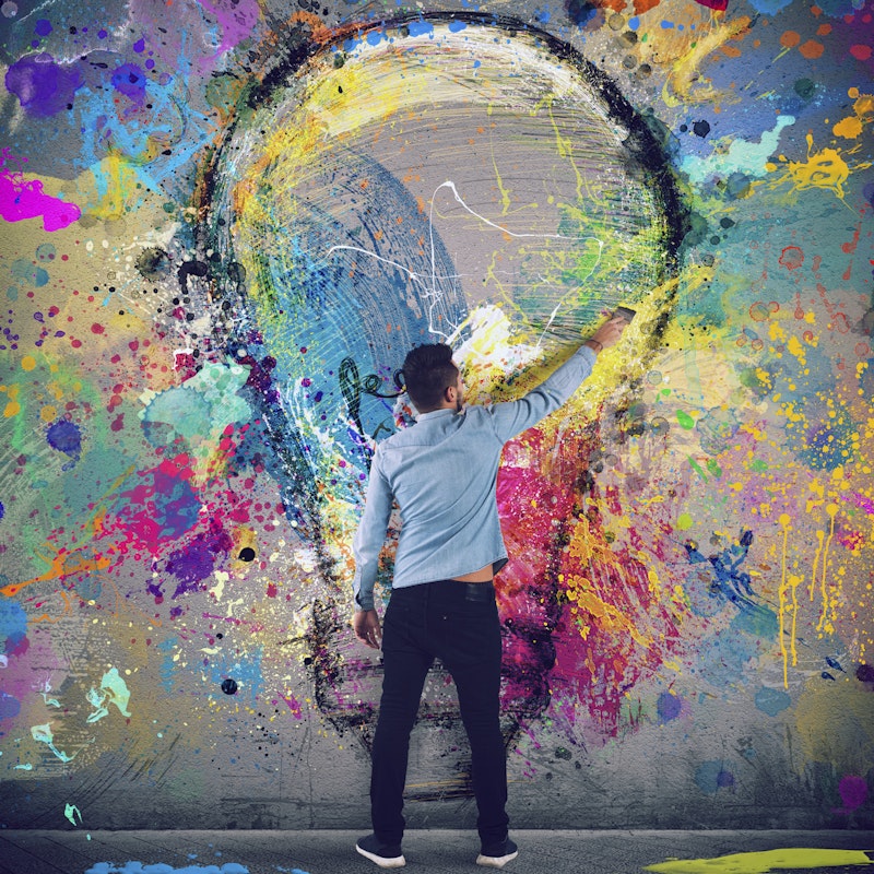  man painting a lightbulb on a wall 