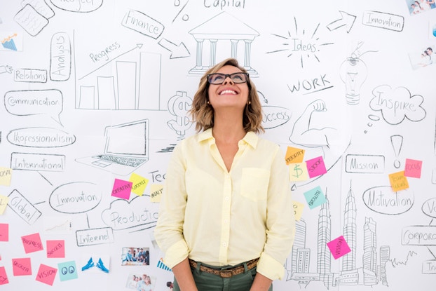  woman standing in front of whiteboard brainstorming