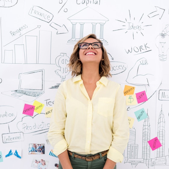 woman standing in front of whiteboard brainstorming