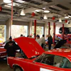 a group of people standing around a car in a garage