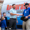 a man shaking hands with a woman and a man standing next to a van