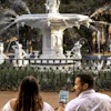 a man and woman sitting in front of a fountain