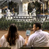 a man and woman sitting in front of a fountain