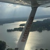a wing of a plane with a body of water and trees