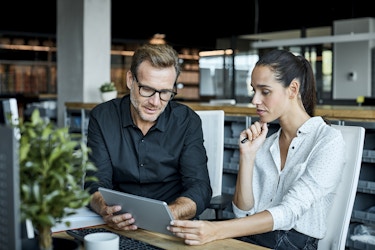 Two business owners sitting down looking at a tablet.