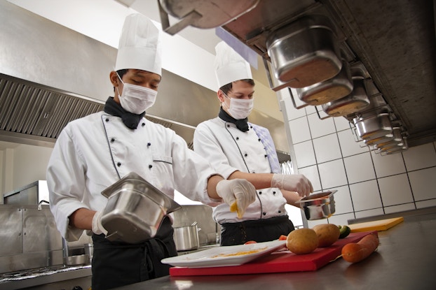 employees working in kitchen wearing masks