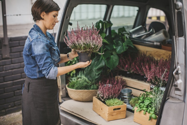 Woman loading flowers into the back of a van.