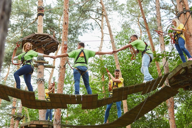 Group of coworkers on a playground bridge during a company retreat.