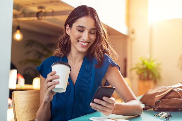  Woman drinking coffee and looking at phone
