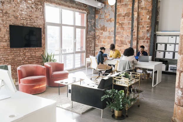 Small team of coworkers sitting at a table in an open coworking space.