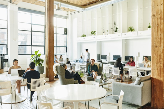 Team of professionals working in groups inside a coworking space.
