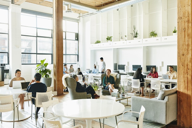  Team of professionals working in groups inside a coworking space.