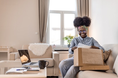  Smiling woman unboxing a package in her living room. 
