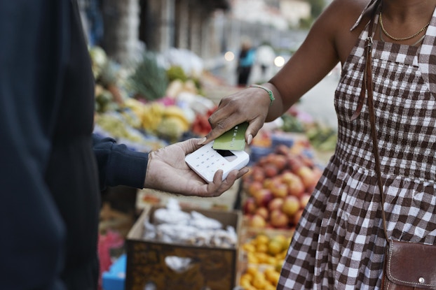  Woman paying at a farmer's market using tap-to-pay with her credit card.