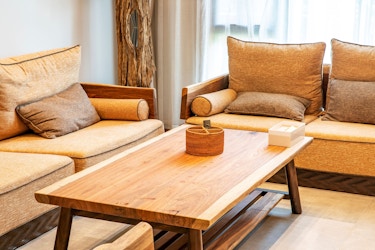 A living room features handmade, wood furniture, including a sofa set and coffee table.