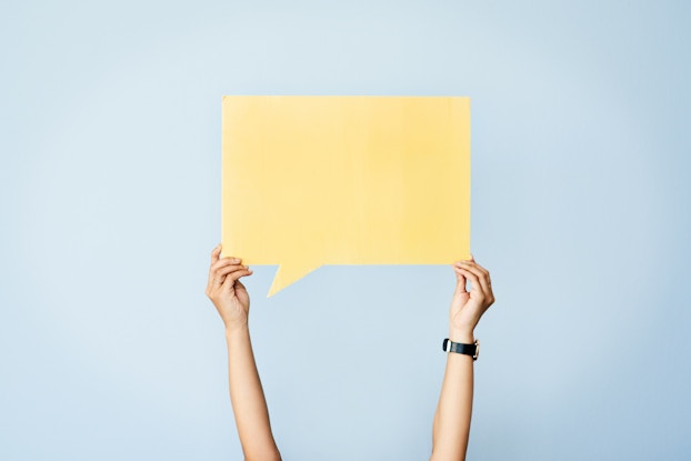 person holding up cutout of conversation bubble