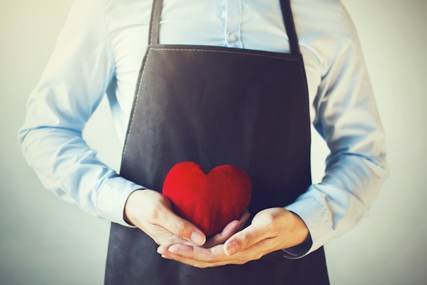 employee wearing apron holding heart