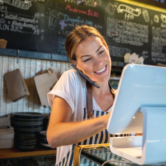 woman on phone and computer in restaurant
