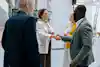A group of business professionals are gathered in a circle. Two of them shake hands.