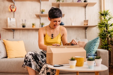  Woman happily unboxing a package inside her home. 