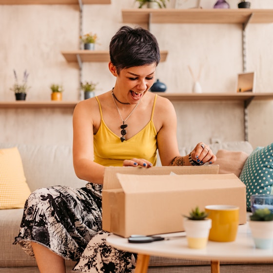 Woman happily unboxing a package inside her home.