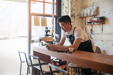  Person working inside a cafe on a tablet. 