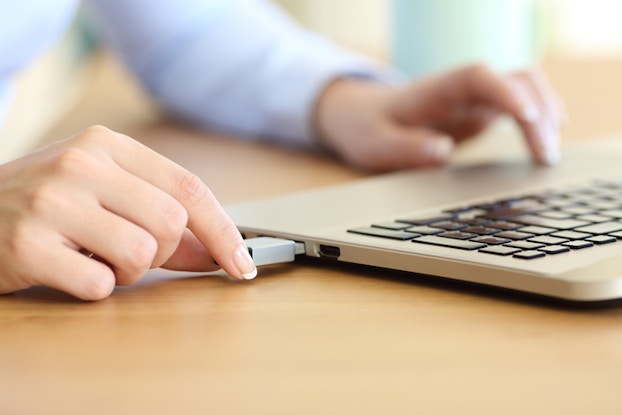 Workers plugging thumb drive into laptop