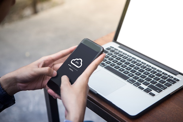 person holding phone with cloud backup icon on screen