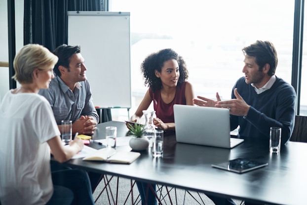  A team of four works around a conference table.