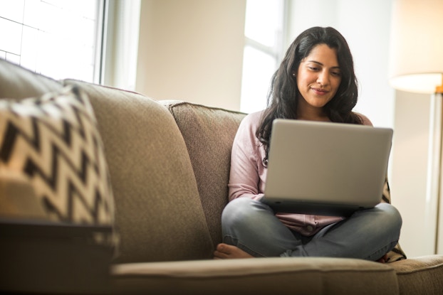  woman sitting on couch working on laptop