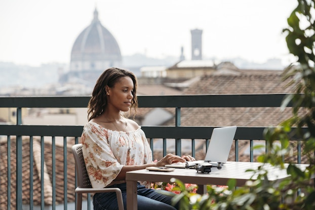 Woman working remotely from an outdoor cafe in Italy.