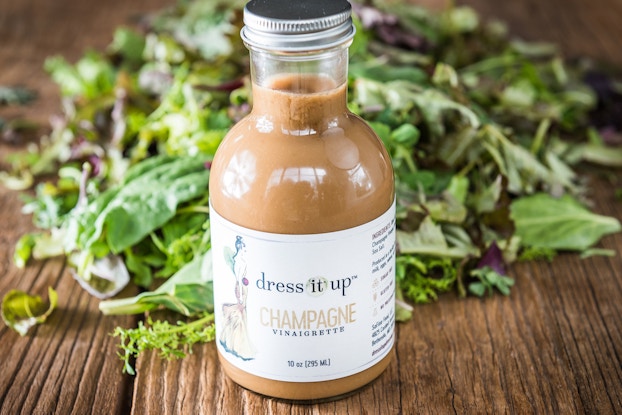 Dress It Up Dressing champagne vinaigrette on a table with a bed of greens