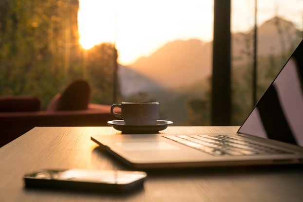 Coffee next to laptop by window