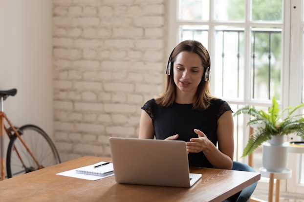  woman working on laptop and using headset at kitchen table