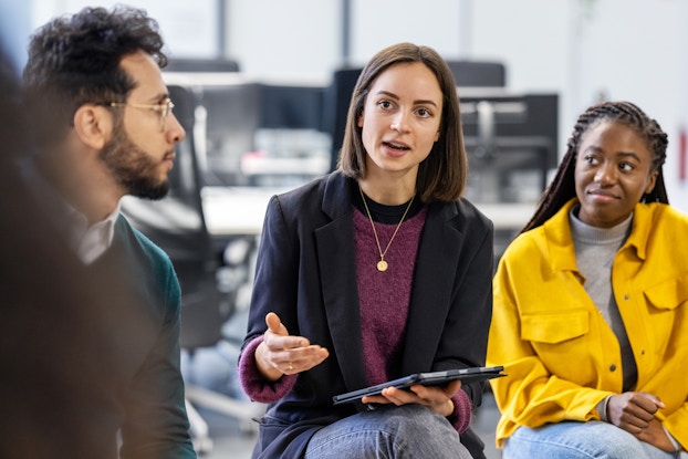 A young woman sharing her ideas with a team sitting in circle at office.