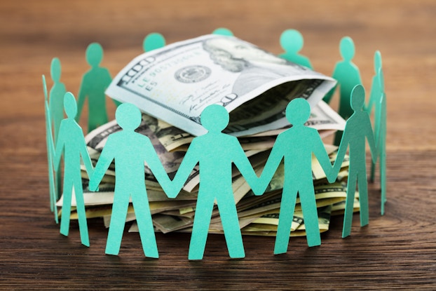  Green paper dolls surrounding a pile of cash