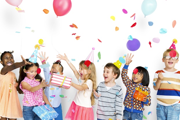  Group of happy kids playing with balloons and confetti.