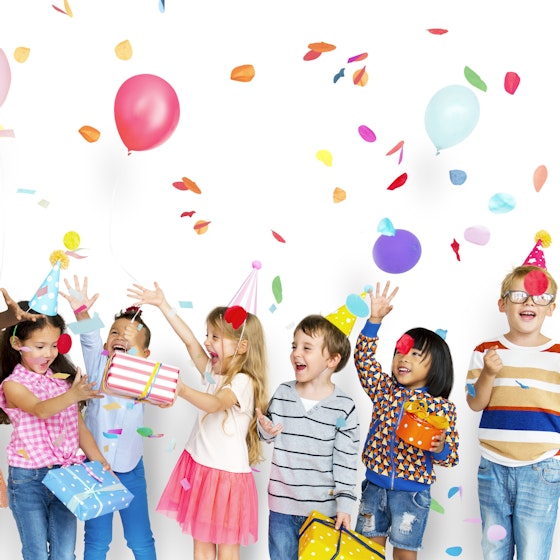 Group of happy kids playing with balloons and confetti.
