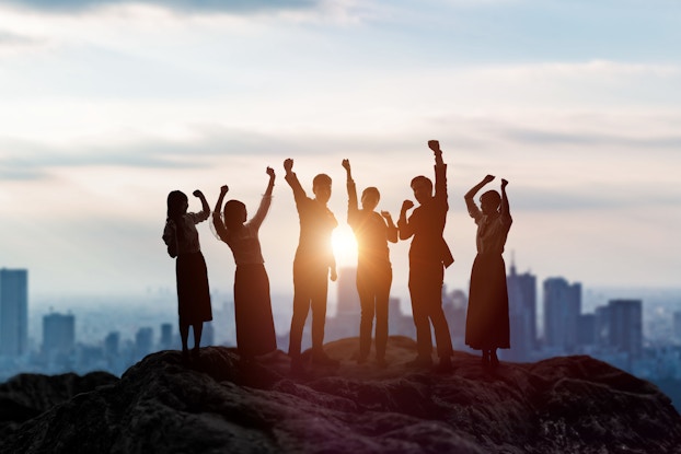 people overlooking city with arms in the air celebrating