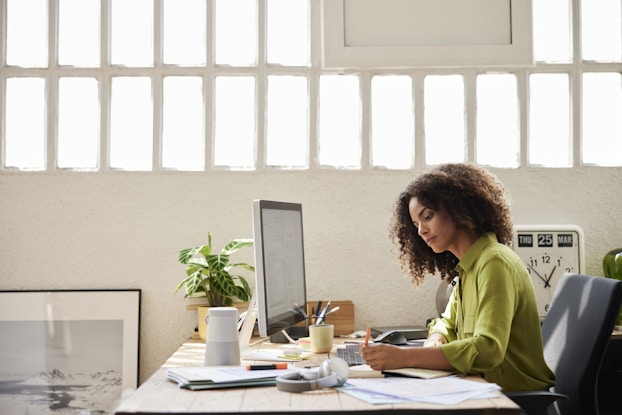 Woman working on laptop at a desk in an office.