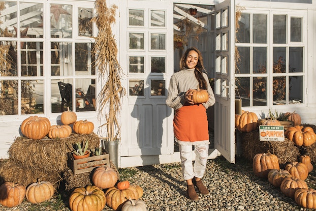 Woman holding a pumpkin at a fall festival.