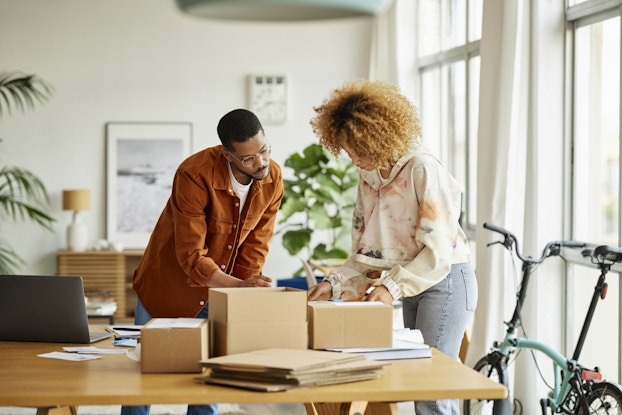 Two people working inside a home office packing boxes.